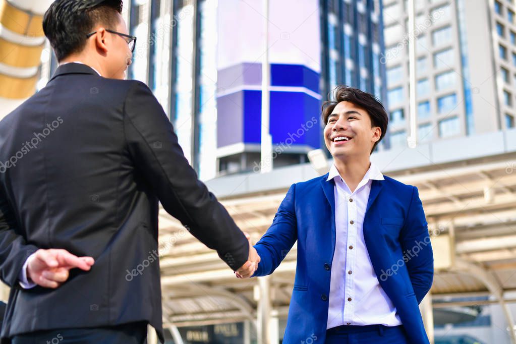 Business concept hypocrisy, Young businessmen shake hands with f