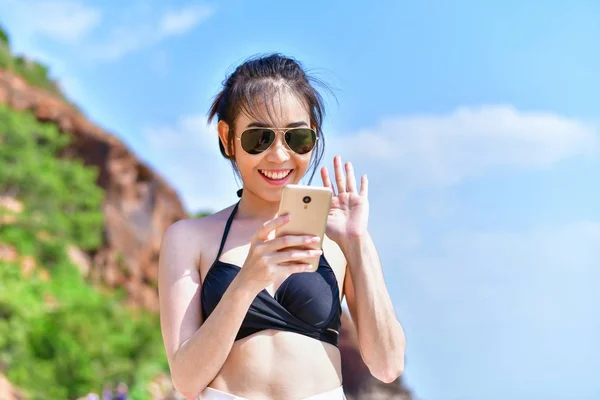 Gyönyörű lány visel a fürdőruha a strandon mobil játék. — Stock Fotó