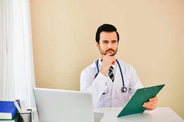 S úsměvem lékař pózuje v kanceláři, má na sobě stetoskop — Stock fotografie