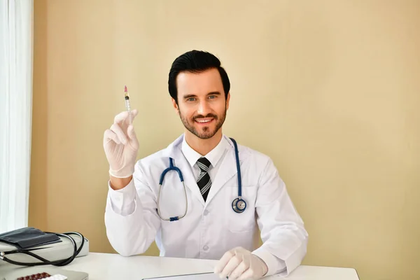 Χαμογελαστός ο γιατρός που ποζάρουν στο γραφείο, φοράει ένα στηθοσκόπιο — Φωτογραφία Αρχείου