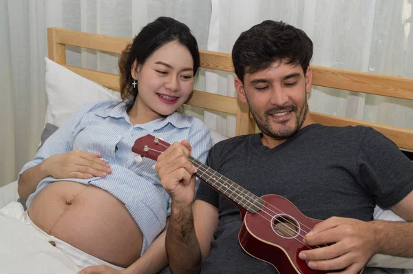 Homens tocando música para mulheres grávidas no quarto . — Fotografia de Stock