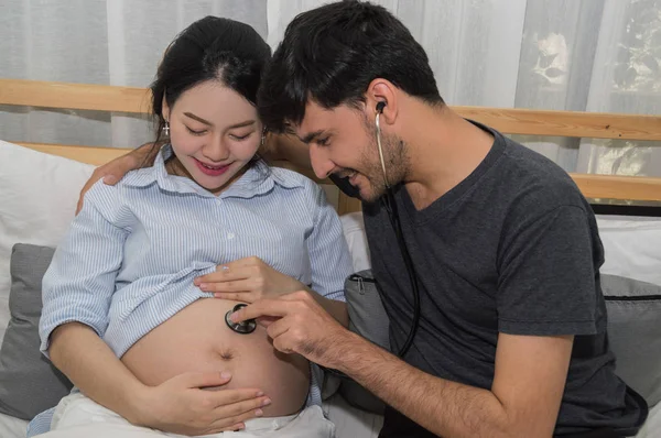 Os homens ouvem mulheres grávidas com um humor feliz em casa . — Fotografia de Stock