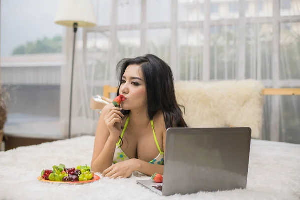 Jonge vrouwen het dragen van ondergoed, spelen een laptop op het bed. — Stockfoto