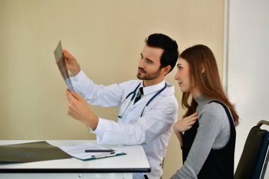 Sağlık kavramları. Doktor ve hasta röntgen filmi ile ilgilenen. Doct