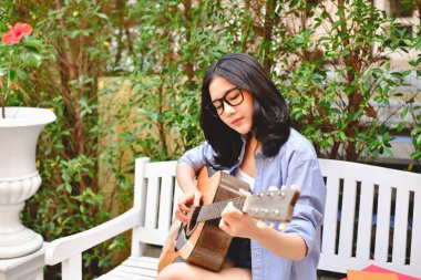 Müzik kavramları. Asyalı kızlar gitar çalmak. Asyalı kadınlar rahatlatıcı