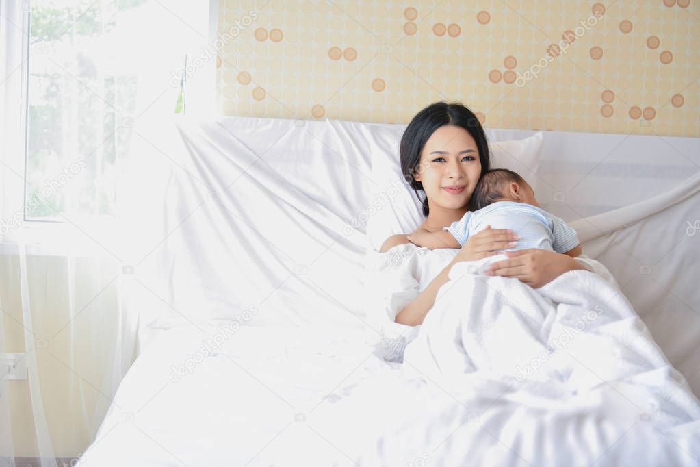 Newborn Concept. Mother and child on a white bed. Mom and baby b
