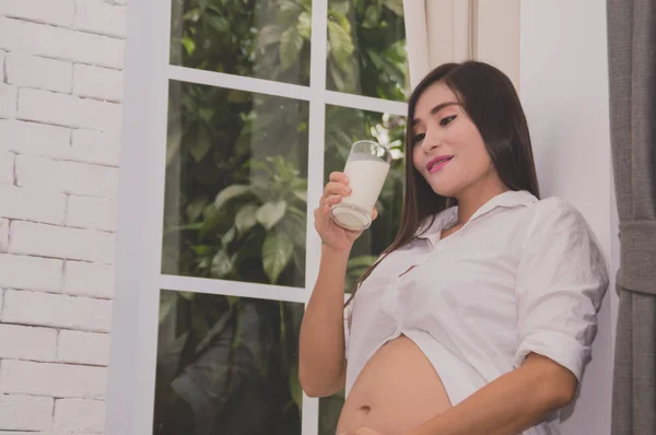 Jovem grávida bebendo leite em casa . — Fotografia de Stock