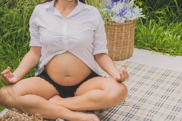 Pregnant women are playing yoga in the garden.