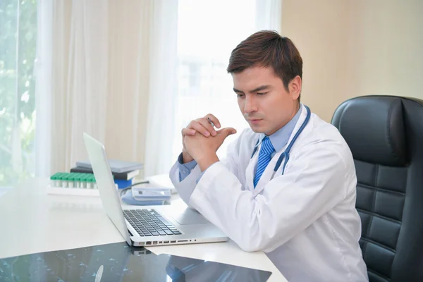 Docteur souriant posant dans le bureau, il porte un stéthoscope — Photo