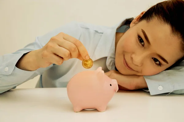 Woman Putting Coin In Piggy Bank, Indoors — Stock Photo, Image