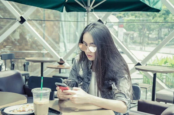 女孩在咖啡馆里玩手机 — 图库照片