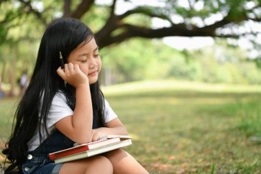 Eğitim kavramları. Kız bahçede bir kitap okuyor. Olmak