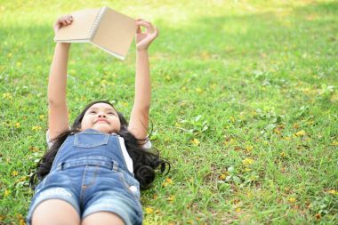 Eğitim kavramları. Kız bahçede bir kitap okuyor. Olmak