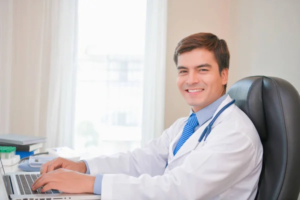 Médico sorridente posando no escritório, ele está usando um estetoscópio — Fotografia de Stock