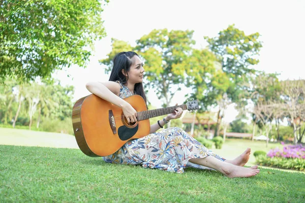 Musikkonzepte. asiatische Mädchen, die Gitarre spielen. asiatische Frauen entspannen — Stockfoto