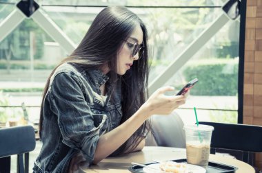 Kız bir kafede mobil oynuyor.