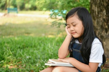 Eğitim kavramları. Kız bahçede bir kitap okuyor. Olmak
