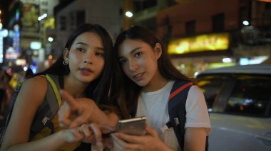 Seyahat konsepti. Aramak için cep telefonu açan genç kadınlar 
