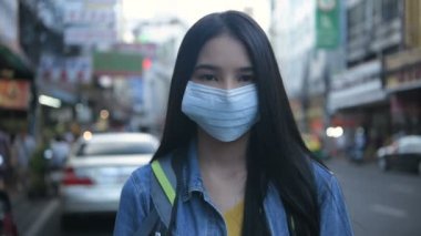 Kirliliği önleme kavramı. Şehrin sokaklarında maske takan güzel bir kadın. 4k Çözünürlüğü.