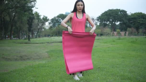 锻炼的概念 年轻女子准备通过在公园里放置瑜伽垫来进行锻炼 4K分辨率 — 图库视频影像
