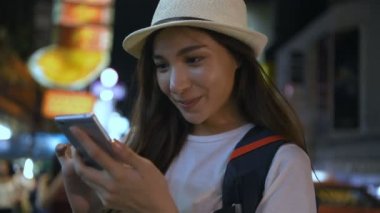 Seyahat konsepti. Güzel kızlar gece şehirde eğlenmek için cep telefonu çalıyorlar. 4k Çözünürlüğü.