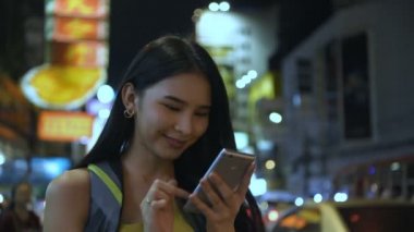 Seyahat konsepti. Güzel kızlar gece şehirde eğlenmek için cep telefonu çalıyorlar. 4k Çözünürlüğü.