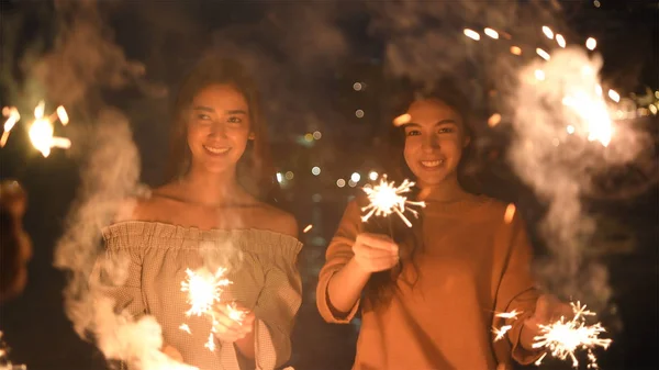 Conceito de férias. Meninas asiáticas jogando fogos de artifício divertidos na praia . — Fotografia de Stock