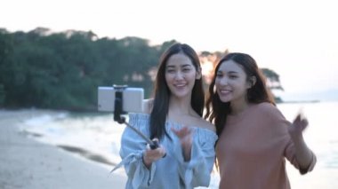 Tatil konsepti. Güzel bir kız kumsalda cep telefonundan videoyu arıyor. 4k Çözünürlüğü.