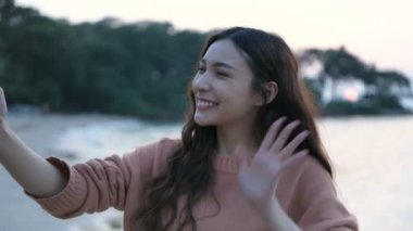 Seyahat konsepti. Güzel bir kız kumsalda cep telefonundan videoyu arıyor. 4k Çözünürlüğü.