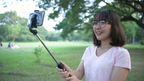 Concepto de vacaciones. Mujeres jóvenes jugando teléfonos móviles en el parque . — Foto de Stock