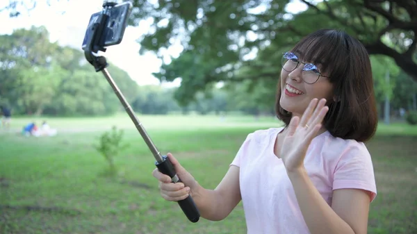 Concepto de vacaciones. Mujeres jóvenes jugando teléfonos móviles en el parque . — Foto de Stock