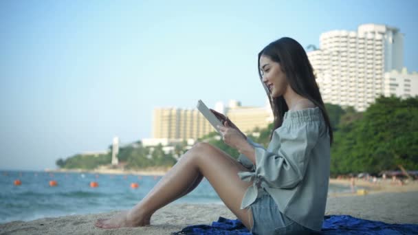 假期的概念 这个女孩在海滩上玩平板电脑很开心 4K分辨率 — 图库视频影像
