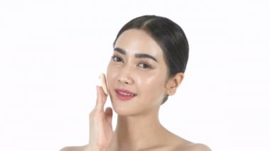 Güzellik konsepti. Güzel bir kız beyaz arka planda yüzüne temel atıyor. 4k Çözünürlüğü.