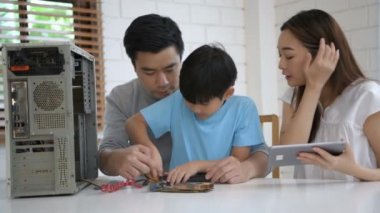 Aile kavramı. Ebeveynler çocuklarını bilgisayar tamir etmeyi öğrenmeleri için teşvik ediyorlar. 4k Çözünürlüğü.