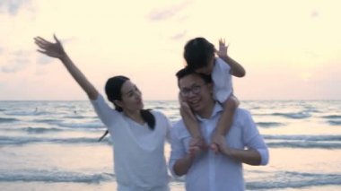 Tatil konsepti. Ebeveynler ve kızları sahilde geziniyorlar. 4k Çözünürlüğü.
