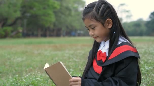 Vzdělávací pojmy. Dívka v maturitních šatech sedí a čte si na zahradě. Rozlišení 4k.