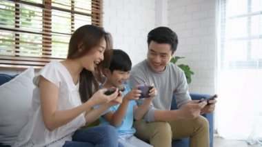 Aile kavramı. Anne ve baba, oğullarıyla oturma odasında oyun oynuyorlar. 4k Çözünürlüğü.