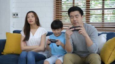 Aile kavramı. Anne ve baba, oğullarıyla oturma odasında oyun oynuyorlar. 4k Çözünürlüğü.