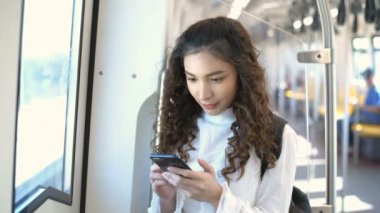 Seyahat konsepti. Trenle seyahat ederken telefonda oynayan güzel bir kadın. 4k Çözünürlüğü.