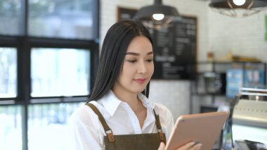 Kahve dükkanı konsepti. Garson kahve dükkanında tabletli müşterilerden sipariş alıyor. 4k Çözünürlüğü.