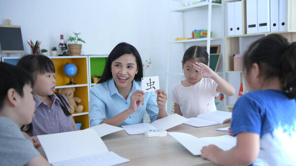 Образовательные концепции. Учитель учит детей учить китайский в классе, с яркой улыбкой на лице
.