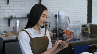 Kahve dükkanı konsepti. Kadın personel tablet kullanarak mağazadaki ürünleri kontrol ediyor. 4k Çözünürlüğü.