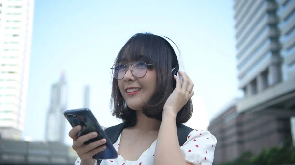 假期的概念 亚洲女孩正在城市里听音乐 4K分辨率 — 图库照片
