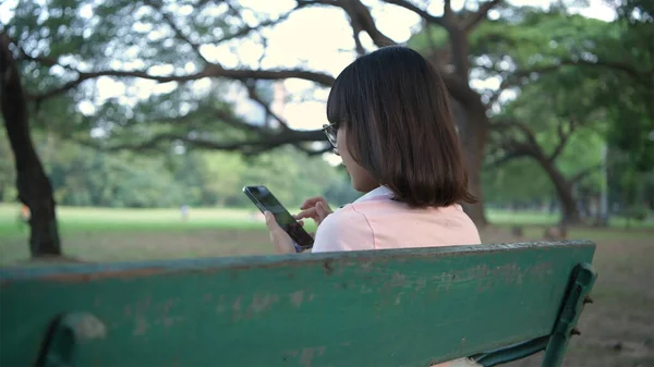 假期的概念 一位亚洲妇女正坐在花园里的手机上 4K分辨率 — 图库照片