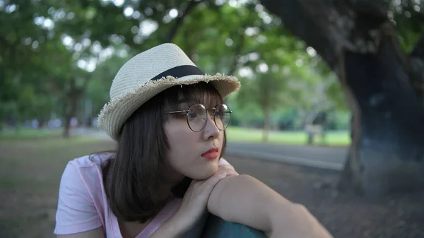 假期的概念 一个亚洲女孩正孤独地坐在花园里的长椅上 4K分辨率 — 图库照片