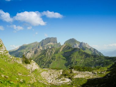 İsviçre Alpleri. Mavi gökyüzünün altında bahar çimenleri olan dağlar. Duvar kağıdı, arkaplan, reklam panosu ya da anasayfanız, sosyal medya ve daha fazlası için kullanışlı.
