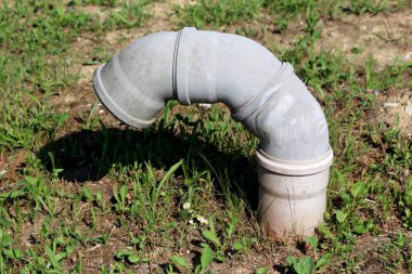 Gri harap olmuş plastik şeker kamışı havalandırma borusu şeklindeydi. Çimlerle ve kuru toprakla çevrili birden fazla bağlantı vardı.