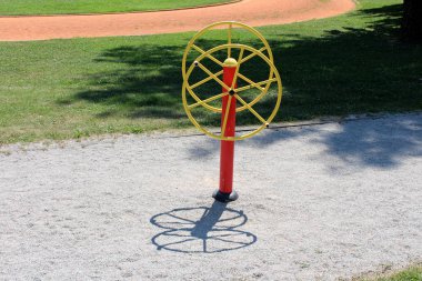 Tai Chi dönüşlü renkli kırmızı ve sarı halka açık park fitness ekipmanı farklı yüksekliklerde iki büyük döner tekerlek ile çakıl ile çevrili ve yerel halk parkında taze kesilmiş çimenler