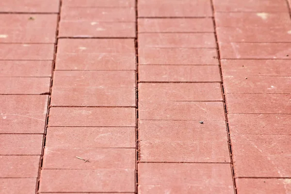 Light red rectangle stone tiles texture at local public park sidewalk on warm sunny summer day wallpaper background