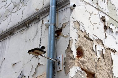 Eski terk edilmiş binanın köşesine monte edilmiş üç yeni kapalı devre TV güvenlik kamerası şehrin eski bölümündeki yeni su borusunun yanında harap olmuş çatlak bir cephe ile birlikte.